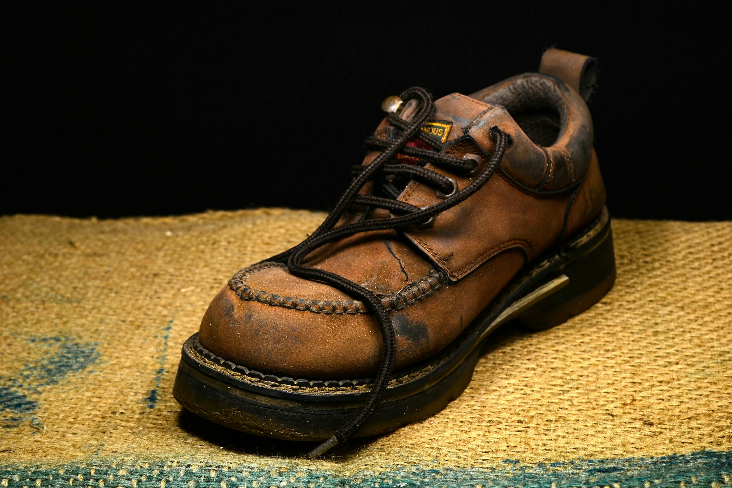 Close-up of a vintage leather boot with worn detailing on burlap.